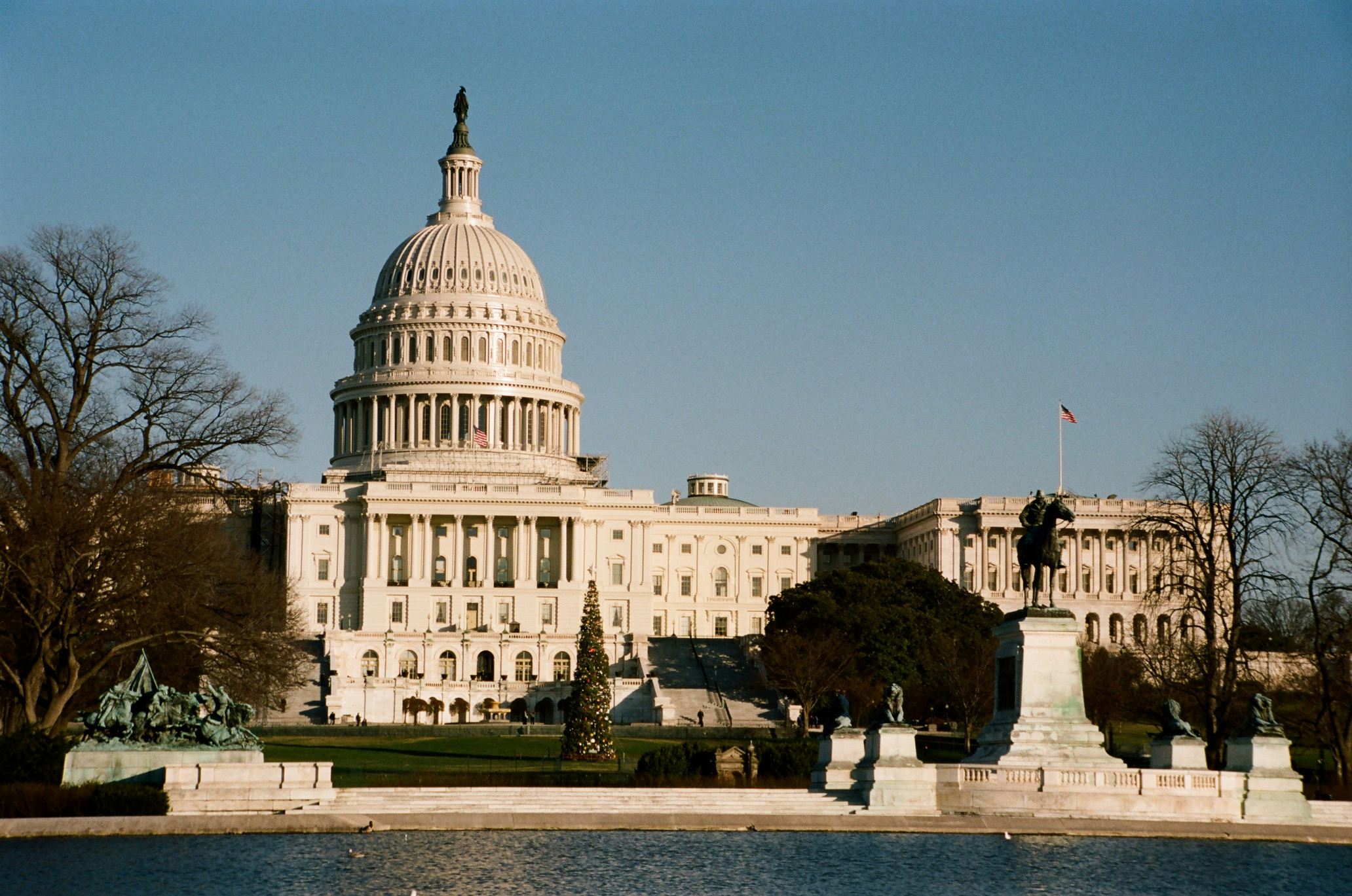 U.S. Capitol building facade with white marble columns and a fountain in the foreground.